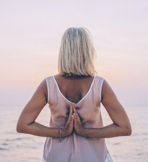Woman in a peaceful yoga pose with a pastel sky and indigo theme.